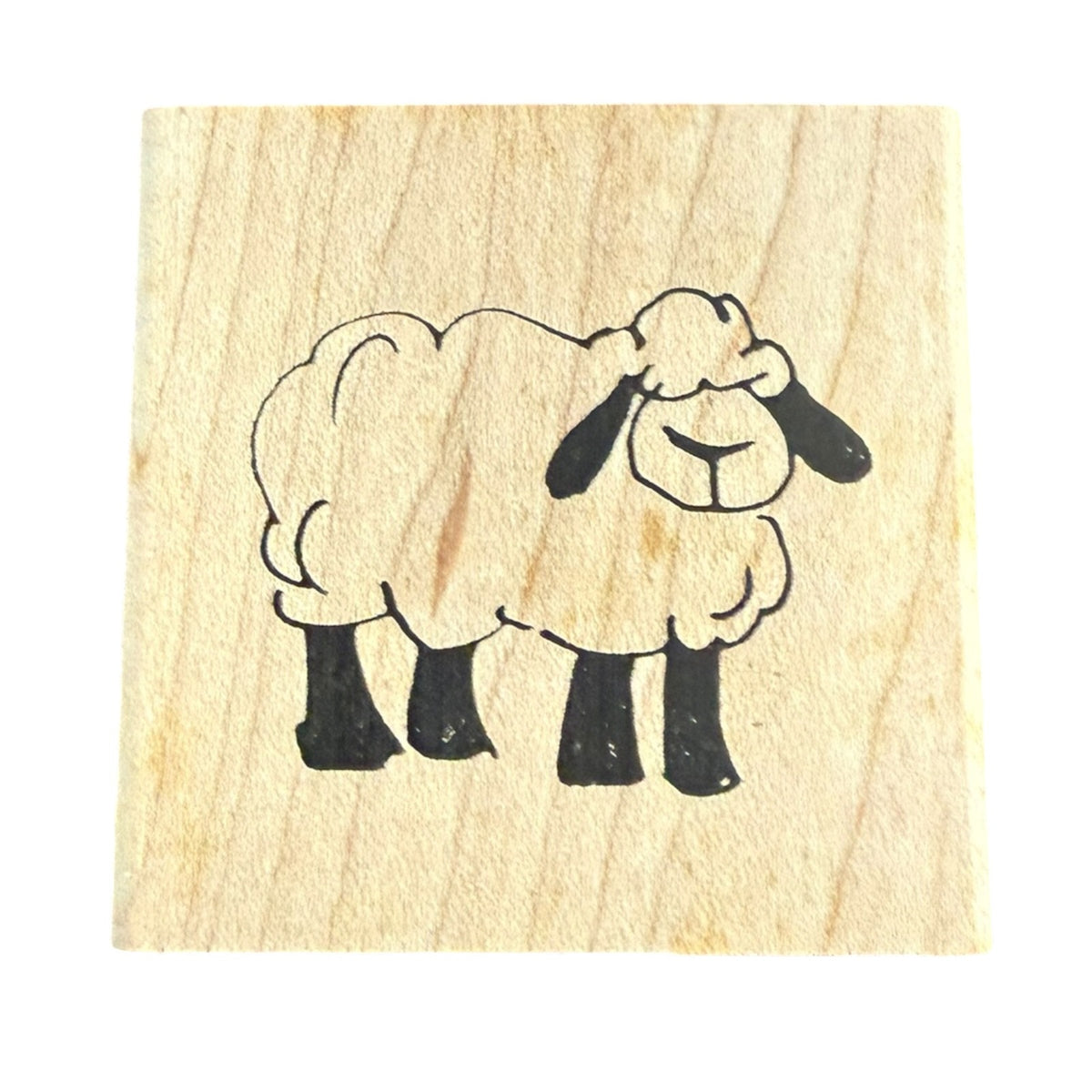A square wooden stamp block featuring a simple black line drawing of a sheep on a light natural wood background, isolated on a white backdrop.