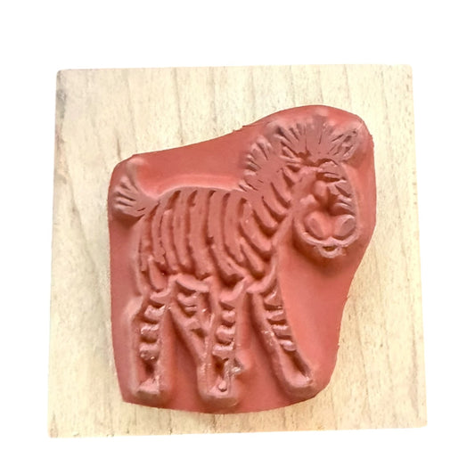 A rubber stamp featuring a zebra design, mounted on a light-colored wooden block against a white background.