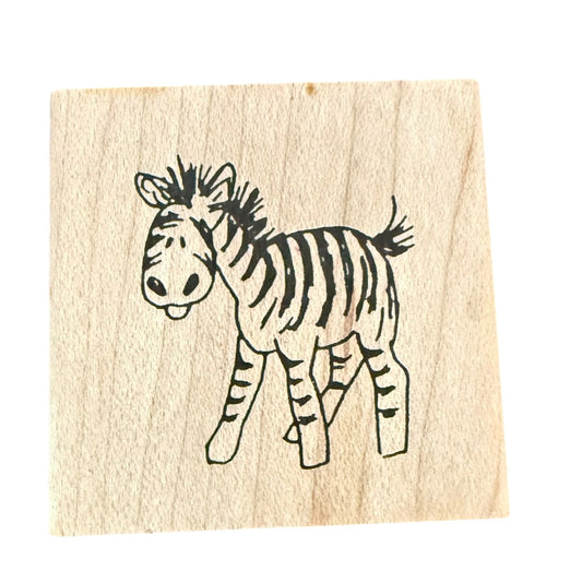 A square wooden rubber stamp featuring a black line-art illustration of a zebra on a light wood grain background, isolated on a white background.