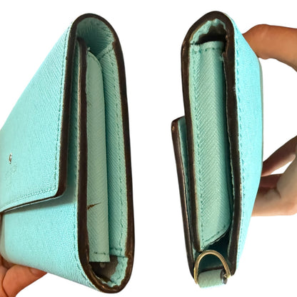 Light blue wallet with brown trim held open to show interior.