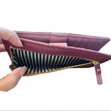 Purple wallet with striped interior held open by a hand on a white background