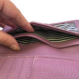 Close-up of a pink wallet with a striped interior on a white background