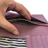 Purple wallet with striped lining held open by a hand on a white background