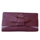 Purple wallet with a bow and 'kate spade New York' logo on a white background