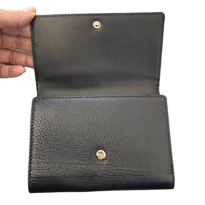 Black leather wallet with gold buttons held open by a hand on a white background