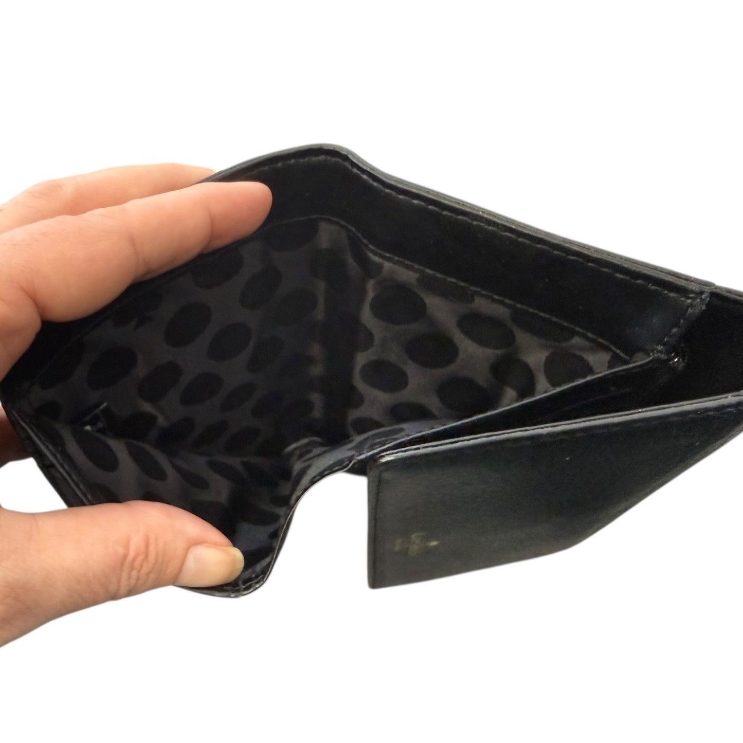 Interior of black wallet pocket held open by a hand on a white background