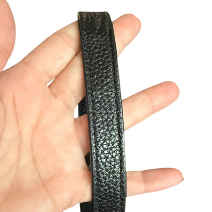 Black leather strap held between fingers on a white background