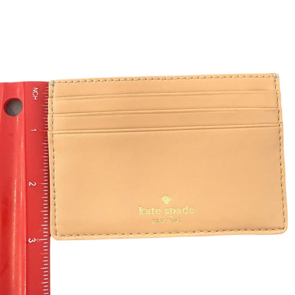 Cardholder with 'kate spade' logo next to a red ruler on a white background