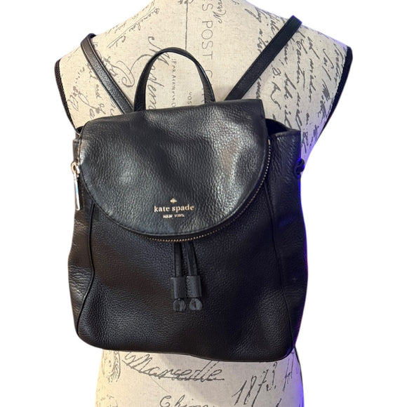 Black backpack with 'kate spade' logo on a mannequin with a script background
