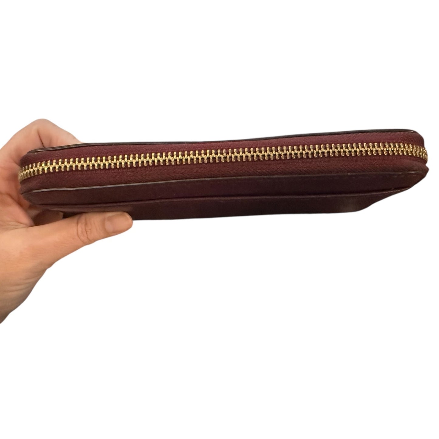 Hand holding a zippered wallet top view  with a gold zipper on a white background