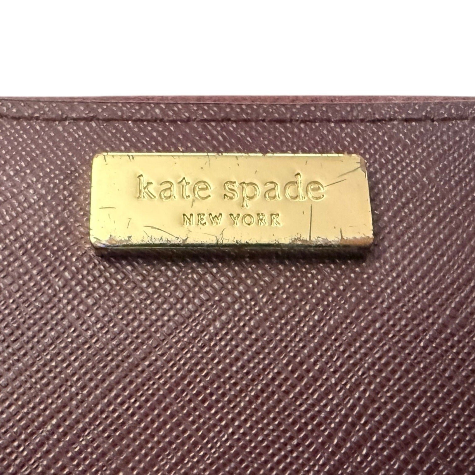 textured wallet with a gold 'kate spade New York' label.