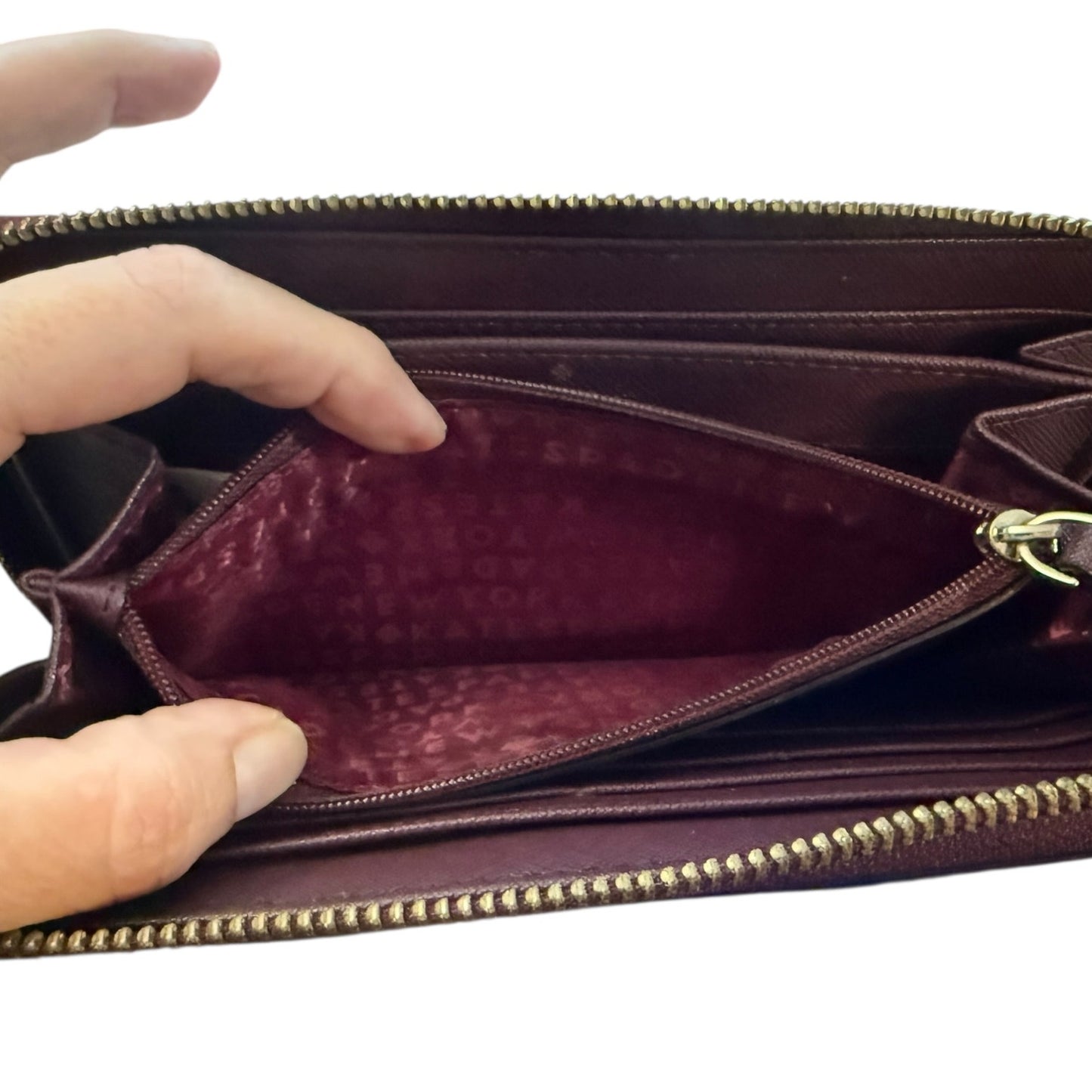 Hand holding a leather wallet with gold zipper