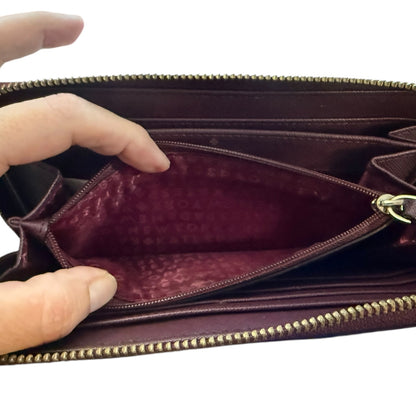 Hand holding a leather wallet with gold zipper