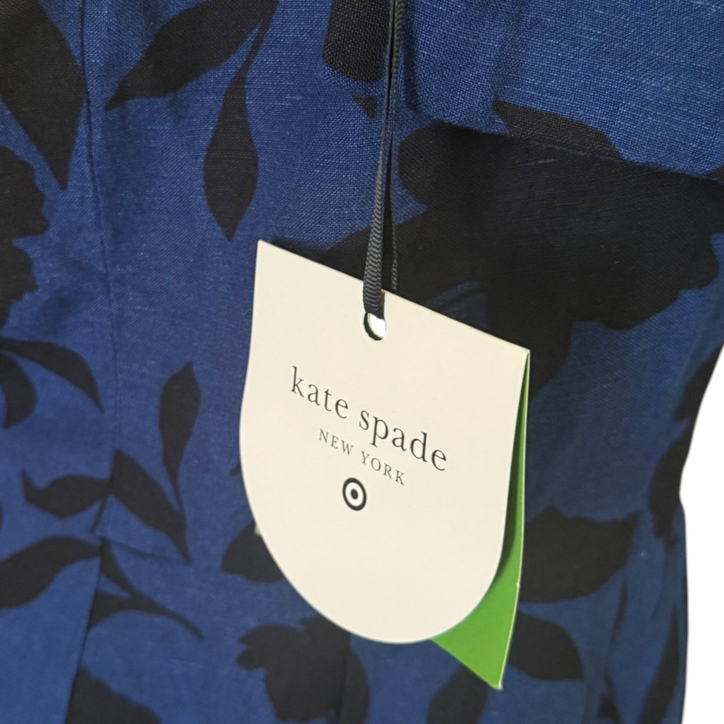 Close-up of a blue and black floral patterned garment with a hanging Kate Spade New York tag.