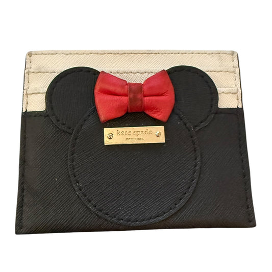 A Kate Spade New York card holder featuring a black Minnie Mouse silhouette with a red bow tie and a gold-tone brand plaque, set against a cream canvas background.