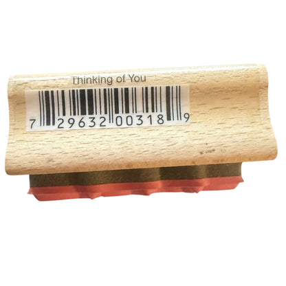 A wooden barcode stamp with the text 'thinking of you' and a barcode printed on the top, showing a red rubber stamp face on a white background.
