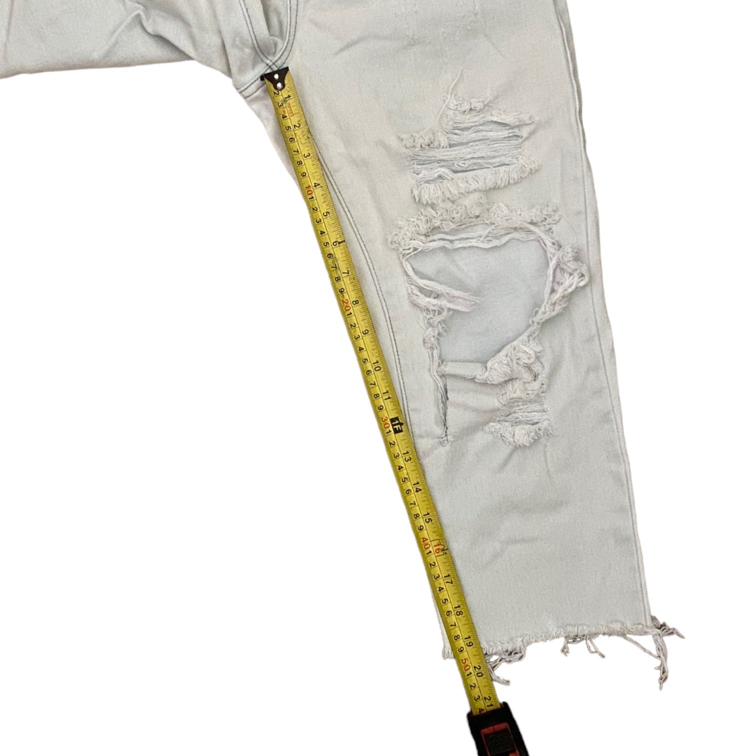 Light blue distressed jeans with a measuring tape on a white background