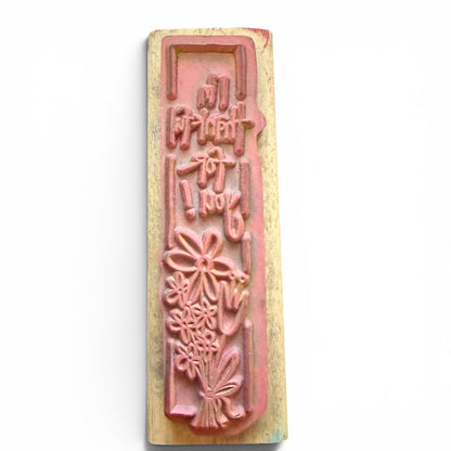 Wooden stamp with floral design and text on a white background