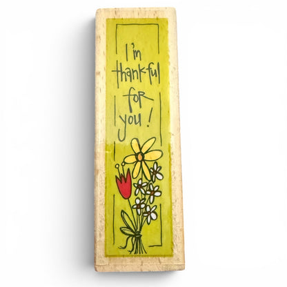 Wooden block stamp with 'I'm thankful for you!' text and floral illustrations on a white background