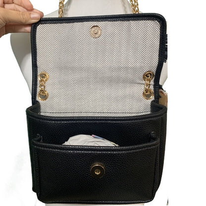 Black handbag held open with gold accents held by a hand on a white background