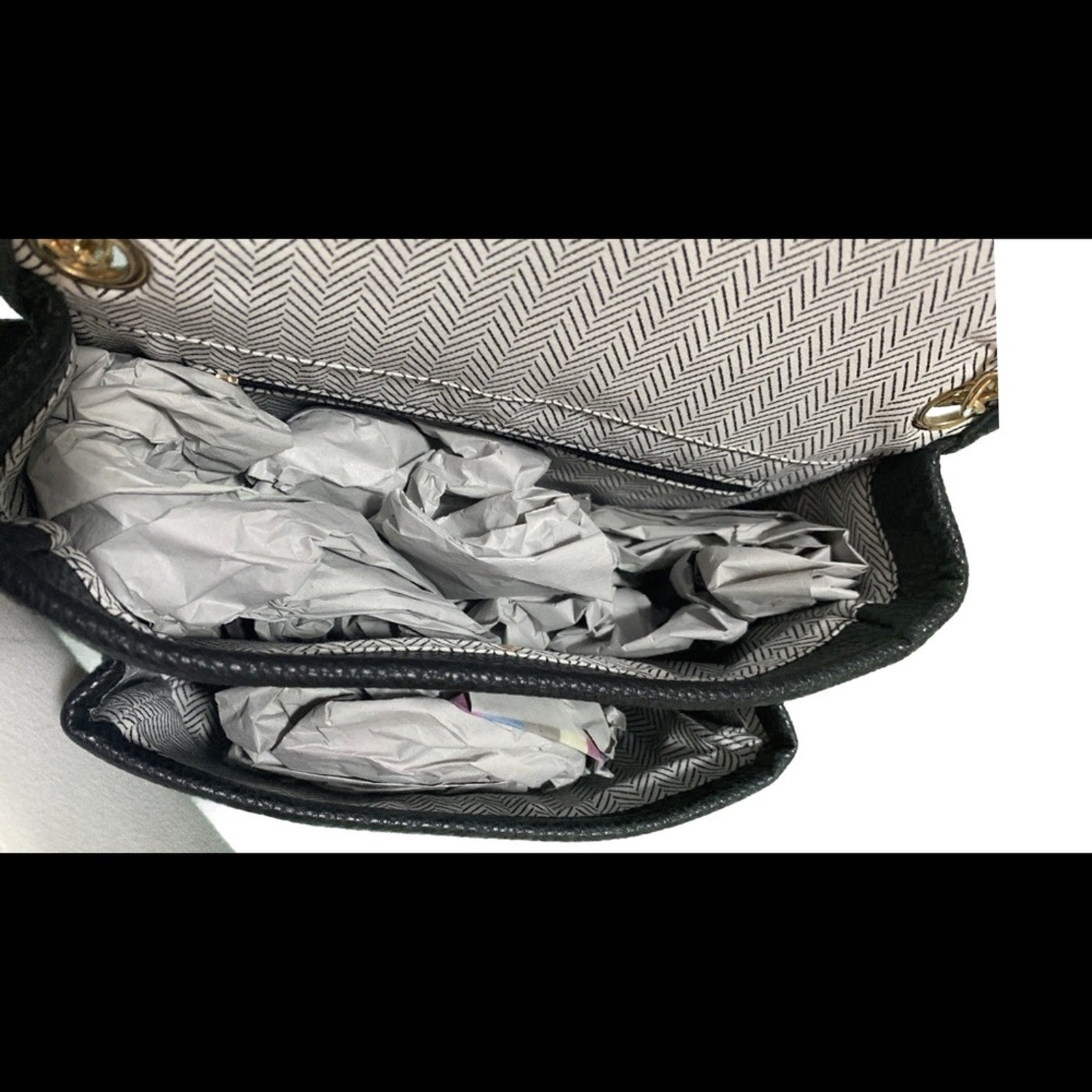 Open handbag with crumpled paper inside on a white background