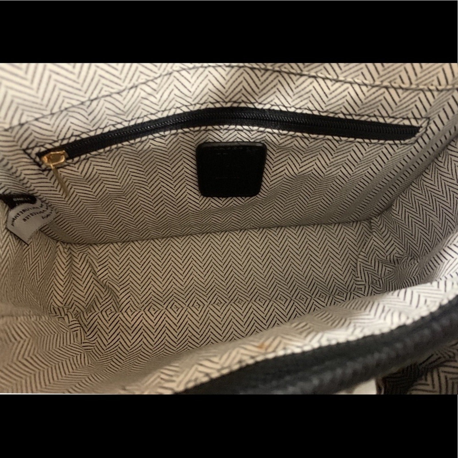 Close-up of a textured bag interior with a zipper and visible brand label.