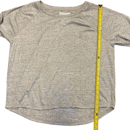 A heather gray short-sleeve crewneck shirt laid flat on a white background, with a yellow measuring tape standing vertically along the right side to show the garment's dimensions.