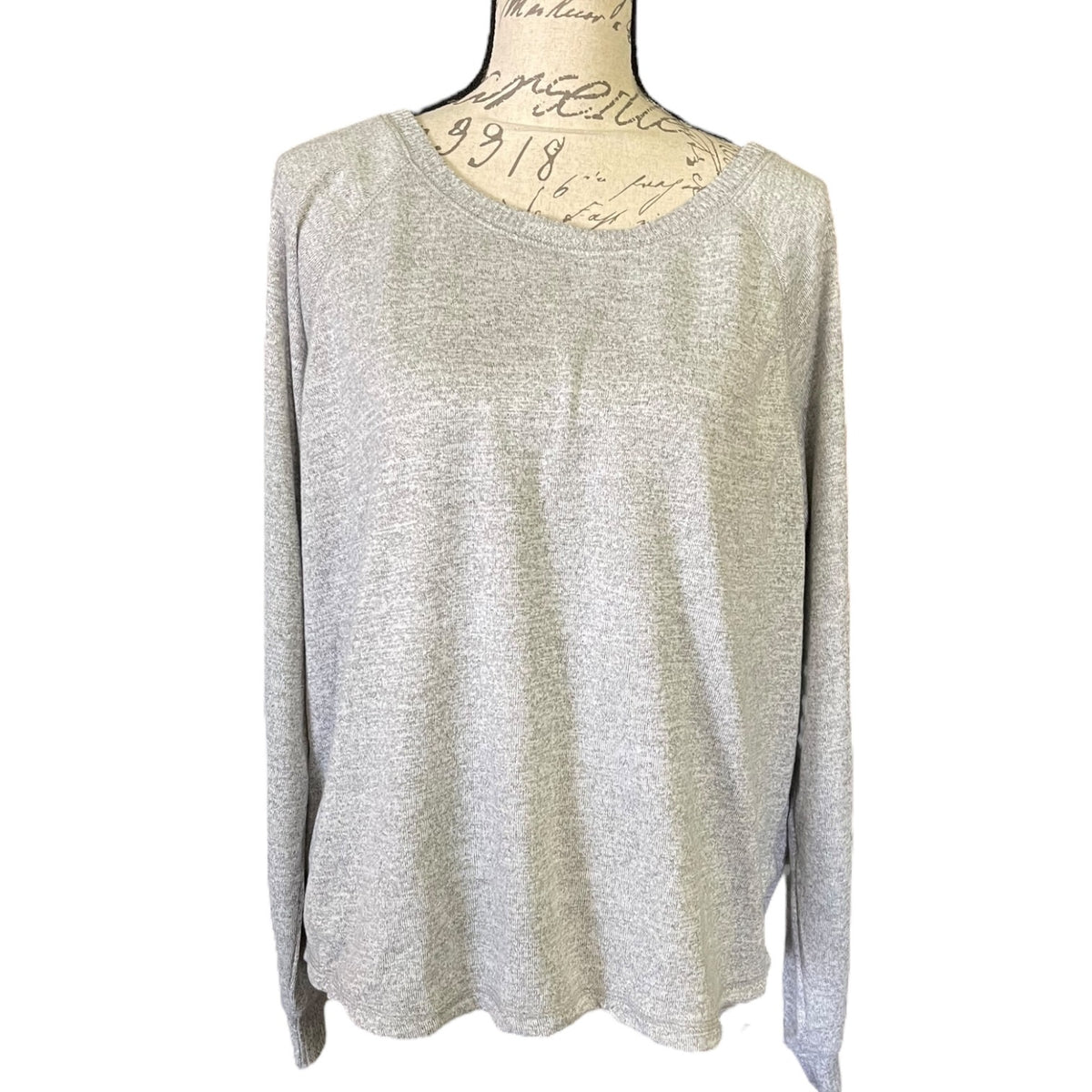 A light gray heathered knit long-sleeve top displayed on a dress form mannequin against a plain white background.