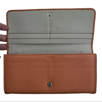 Orange wallet being held popen showing interior with pockets on a white background. 