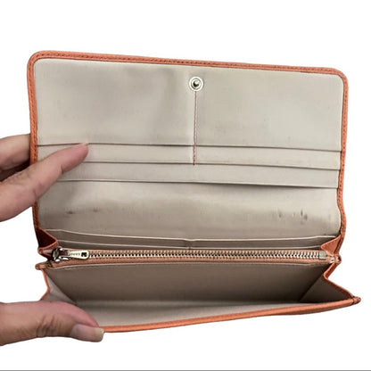 An open wallet with orange leather trim, held open by two hands against a white background.