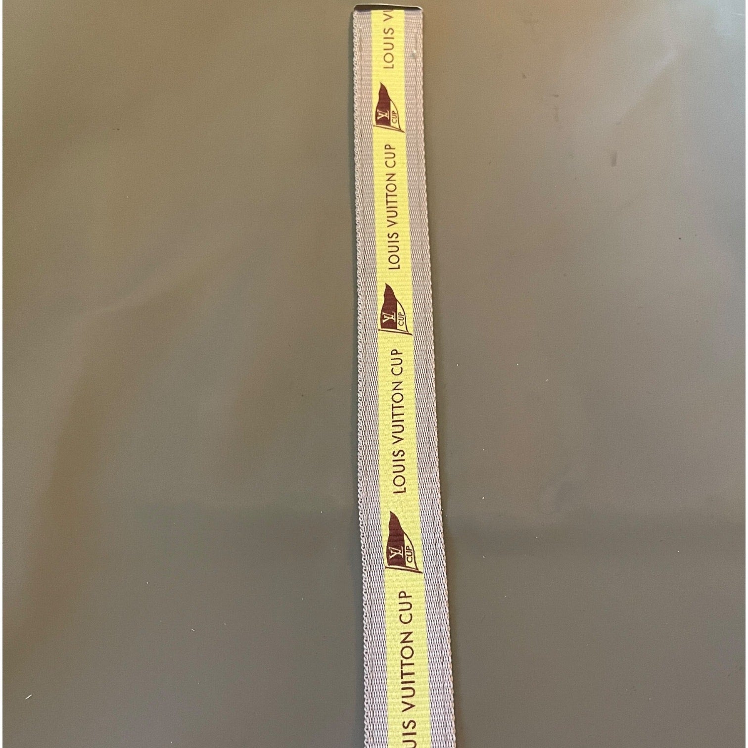 Louis Vuitton cup tote with yellow label on a gray background