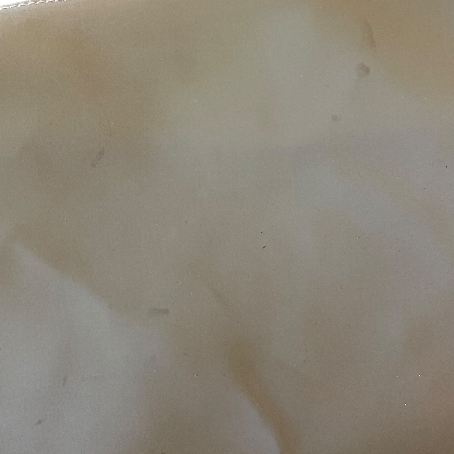Close-up of a beige fabric surface with visible texture and slight imperfections with dirt and marks.