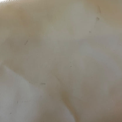 Close-up of a beige fabric surface with visible texture and slight imperfections with dirt and marks.