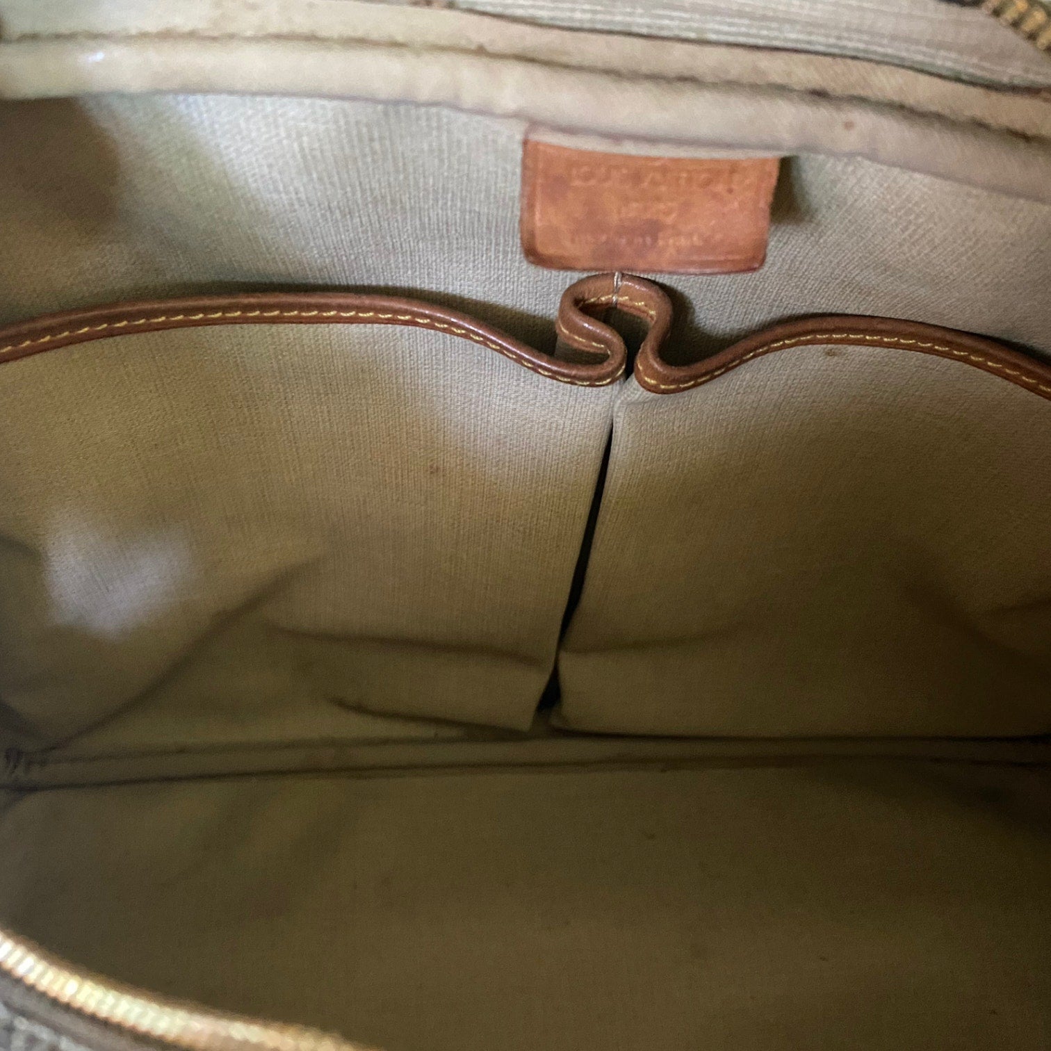 Close-up of a interior with beige lining with a leather patch and stitching detail.