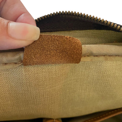 Close-up of a hand holding a brown leather tab