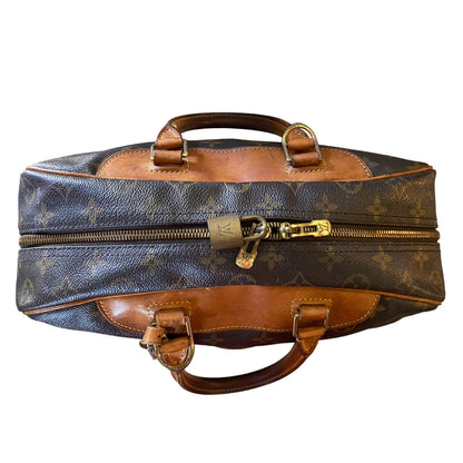 Top of Designer handbag with monogram pattern and gold hardware on a white background