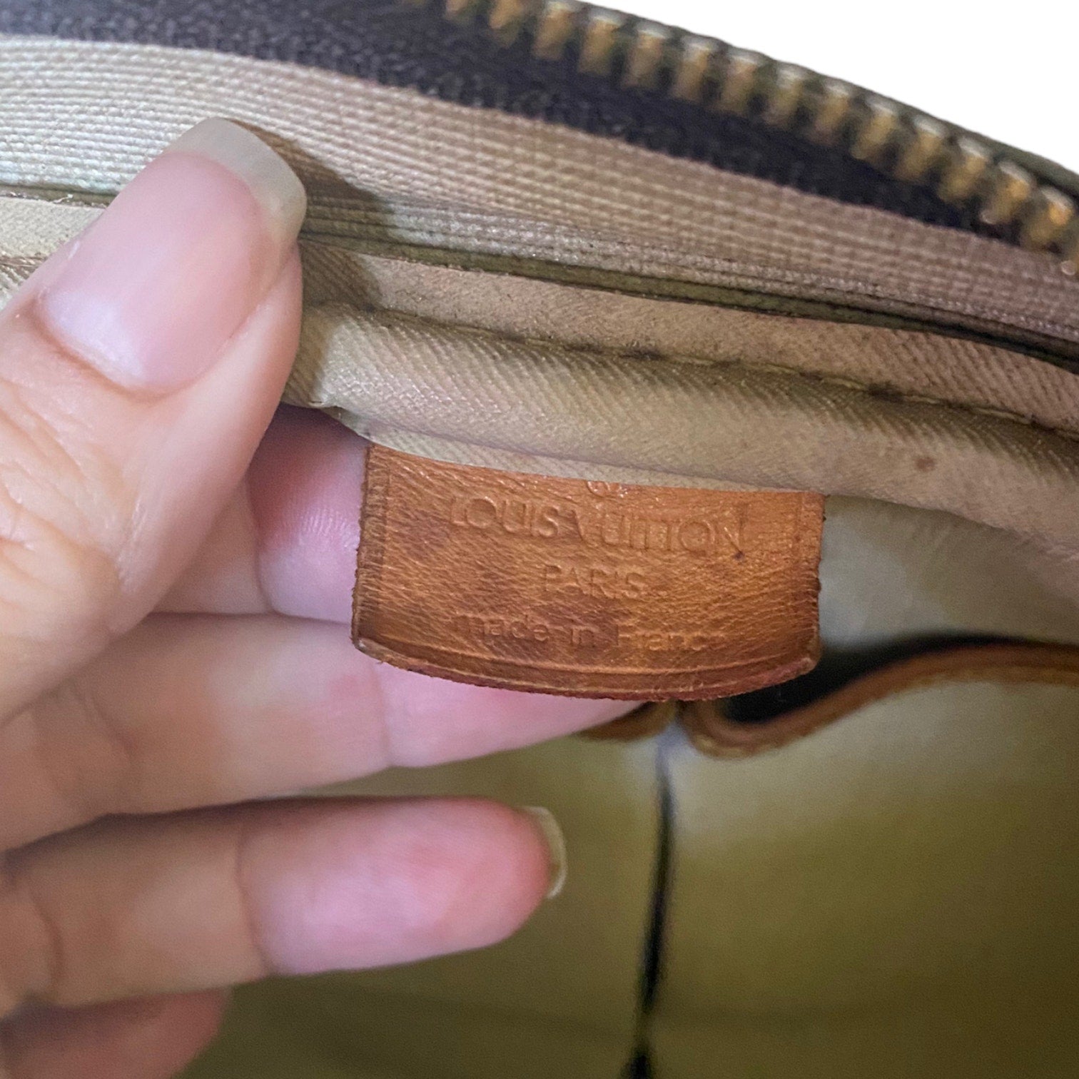 Louis Vuitton logo on a bag with a hand holding it