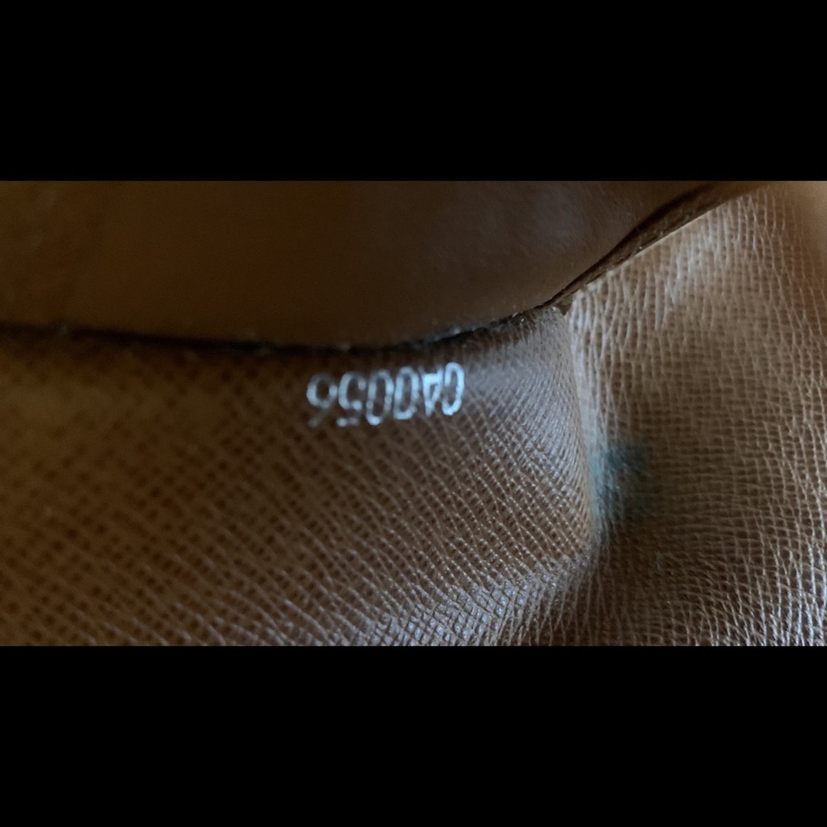 Close-up of a brown textured leather or coated canvas surface with a small white stamped number near the center.