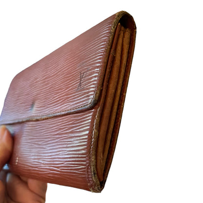 A brown textured leather wallet held by a hand against a plain white background.