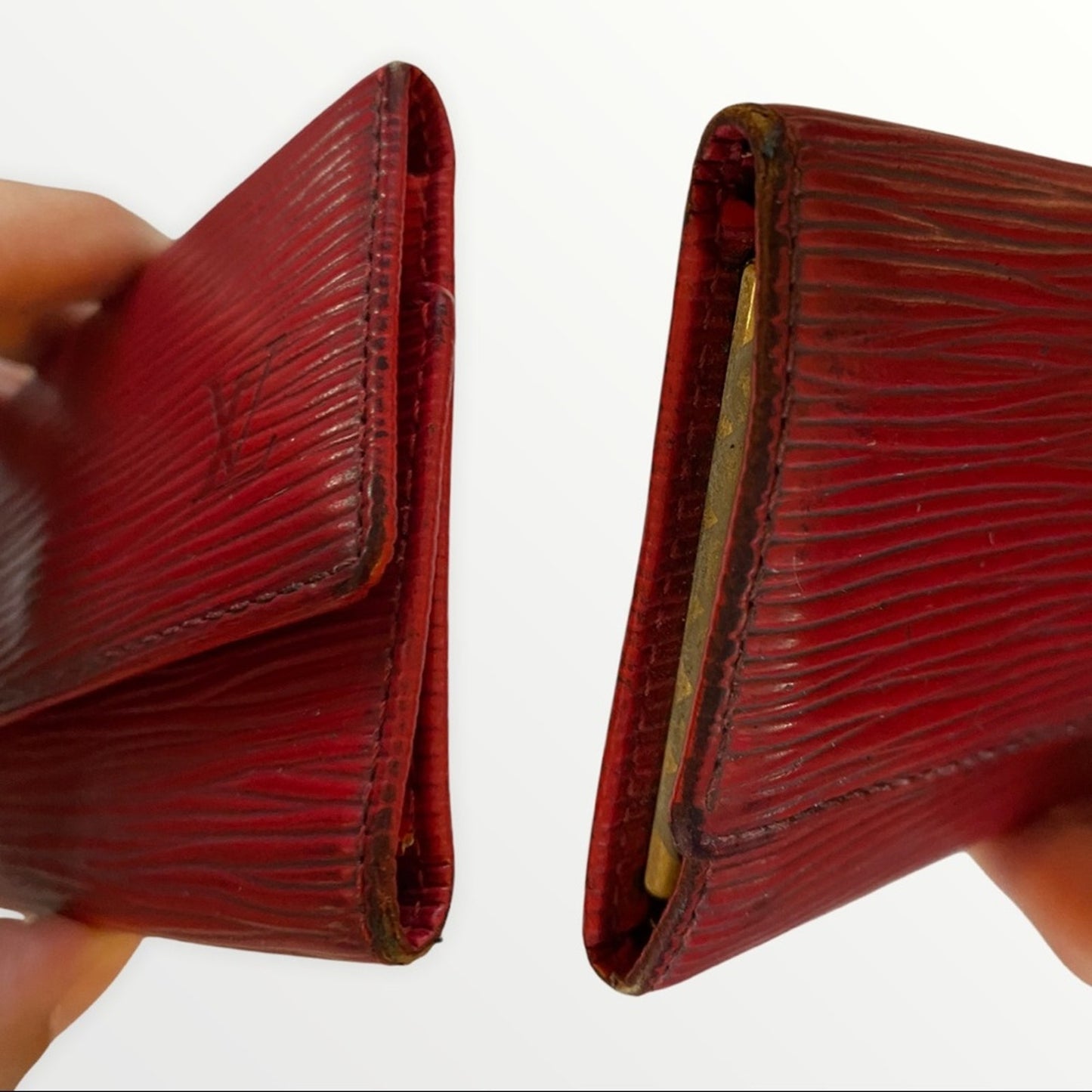 A red textured leather key wallet shown from both sides, held by hands against a plain white background. 