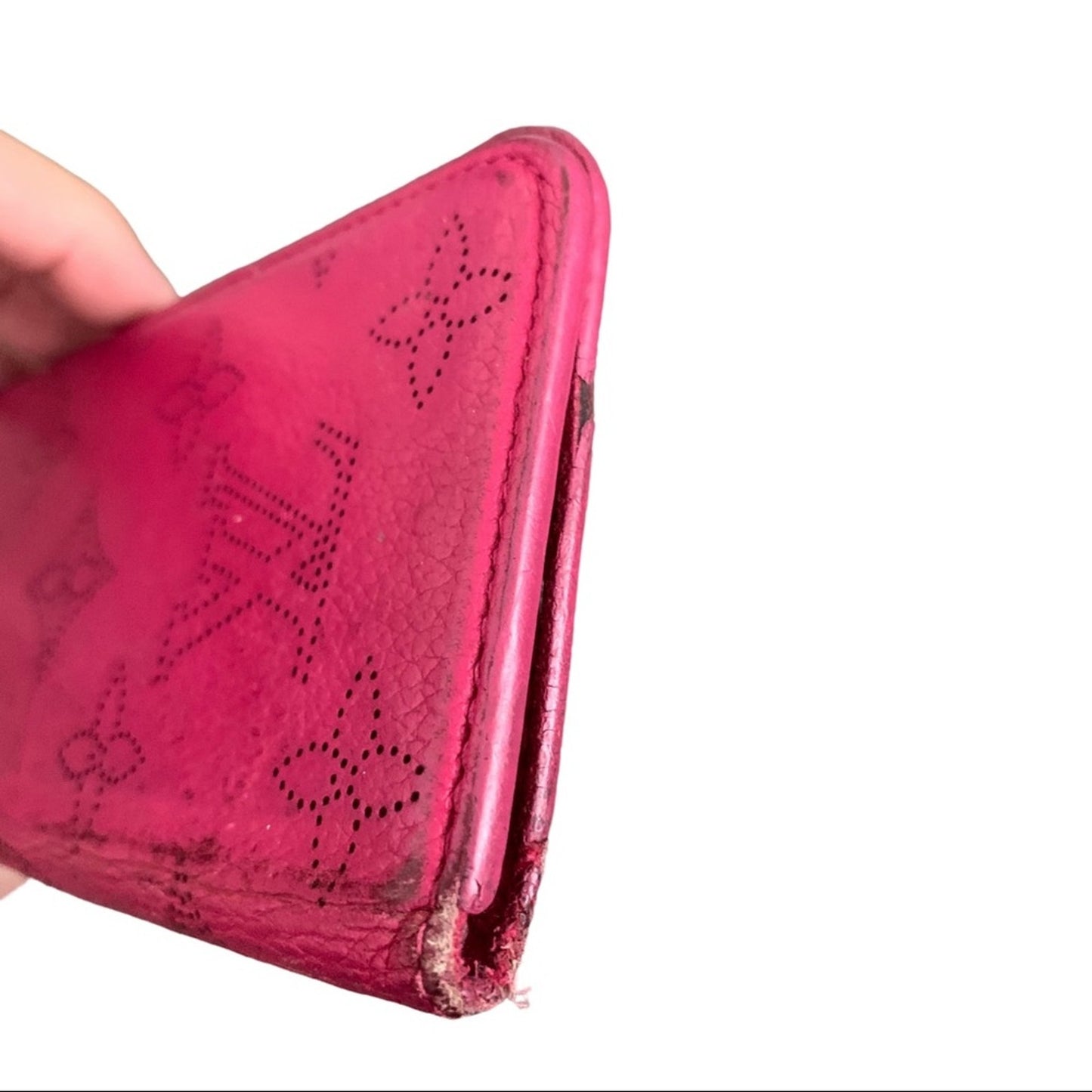 Pink cellphone case with monogram patterns held by a hand showing edges on a white background