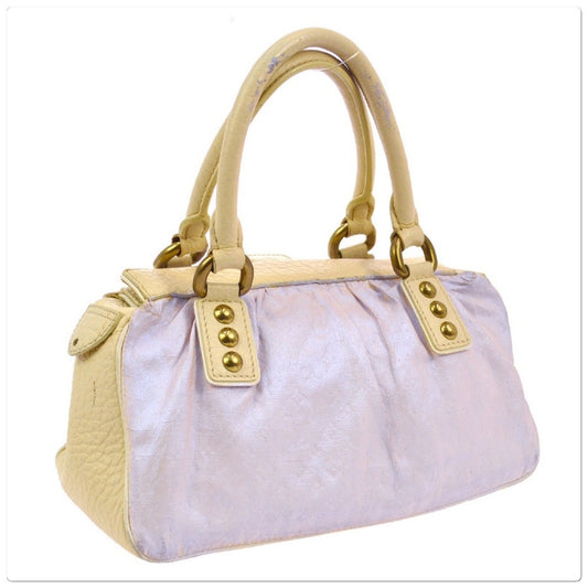 A light lavender-purple textured handbag with leather handles and trim, accented by gold-tone metal hardware.