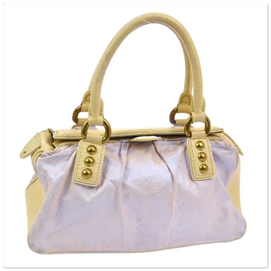 A small handbag with a metallic pale lavender body, beige leather handles and trim, and gold-tone hardware, shown on a plain white background.