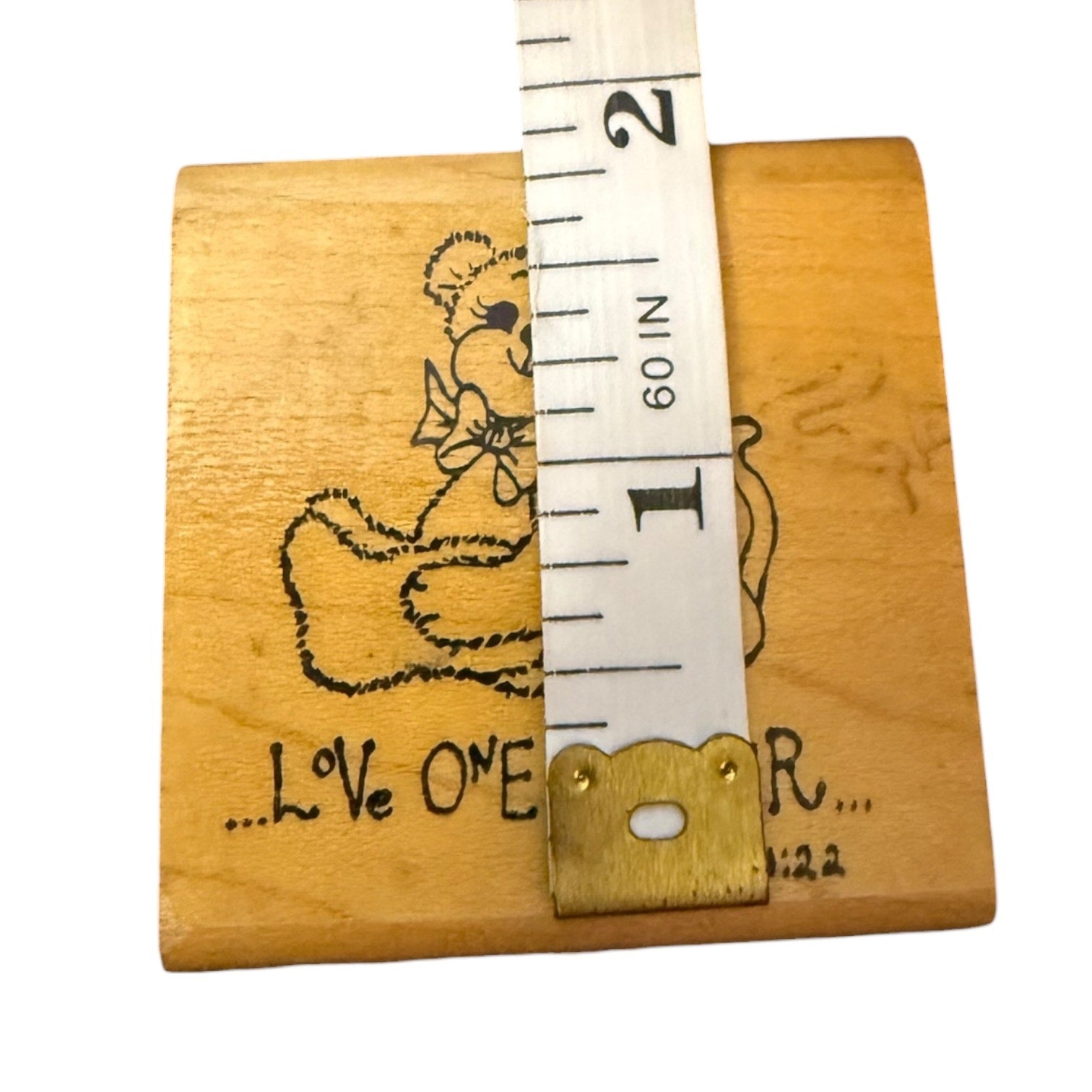 Wooden block with engraved design and measurement tape on a white background