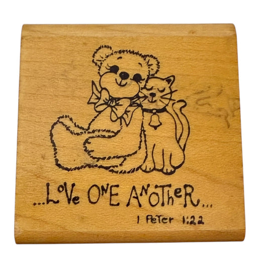 Wood block with a bear and cat illustration and 'Love One Another' text on a white background