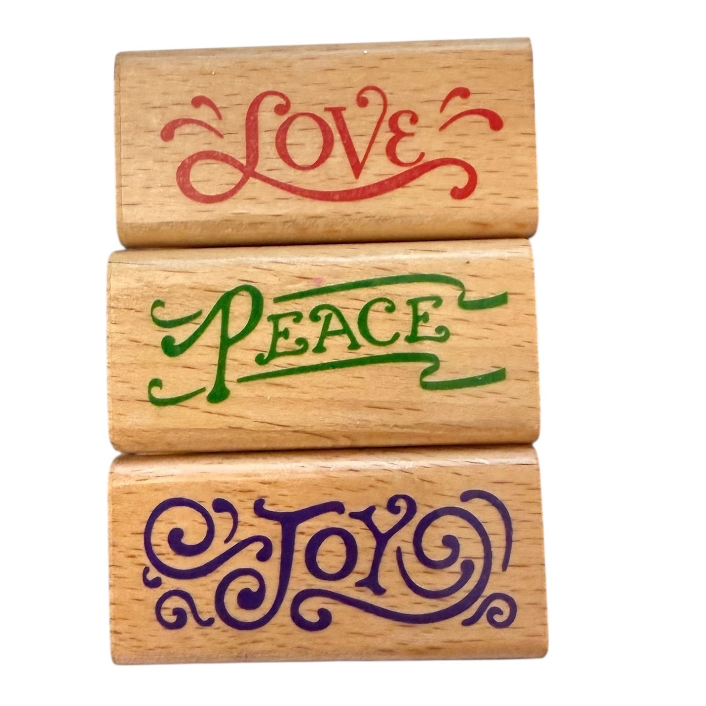 Three wooden stamps with 'Love', 'Peace', and 'Joy' engraved on them.