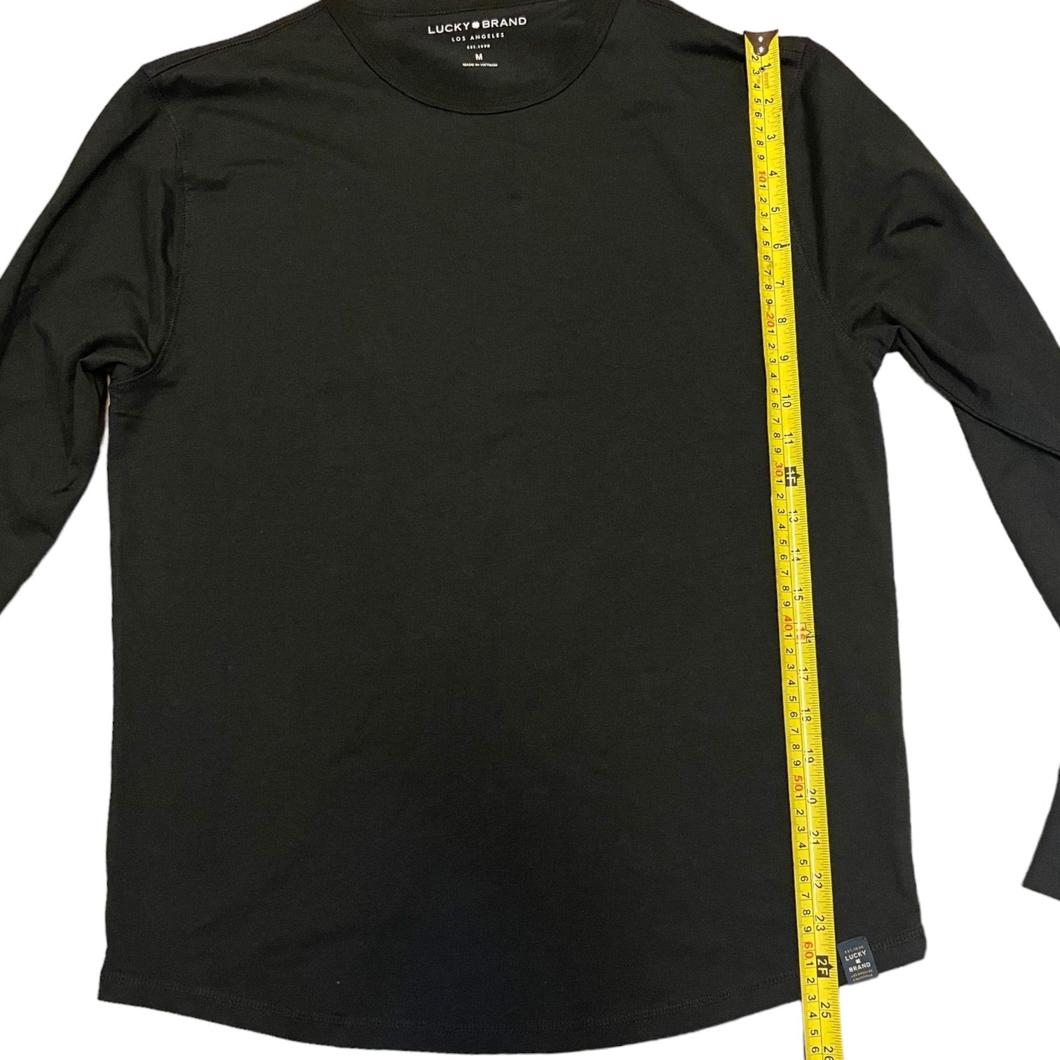 Black long-sleeve shirt with a measuring tape on a white background