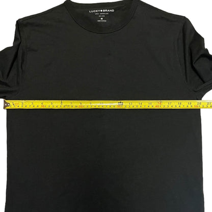 Black shirt with a measuring tape across it, displaying the brand 'Lucky Brand'.