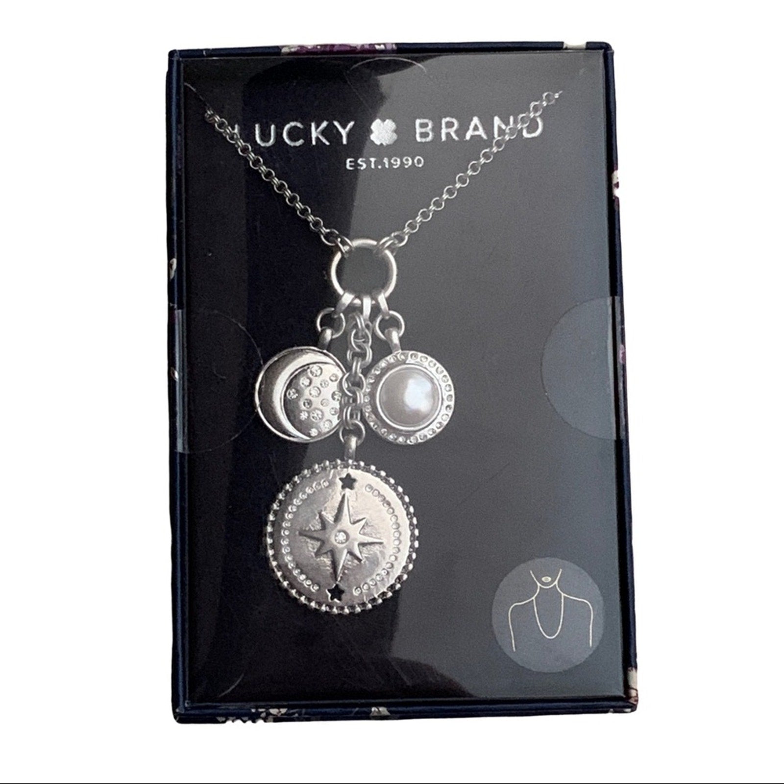 Silver necklace with charms on a Lucky Brand packaging