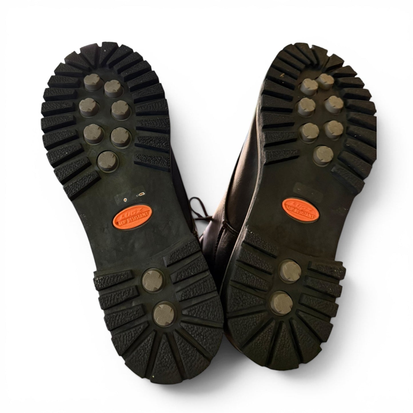 Bottom of shoes that are black with orange labels on a white background